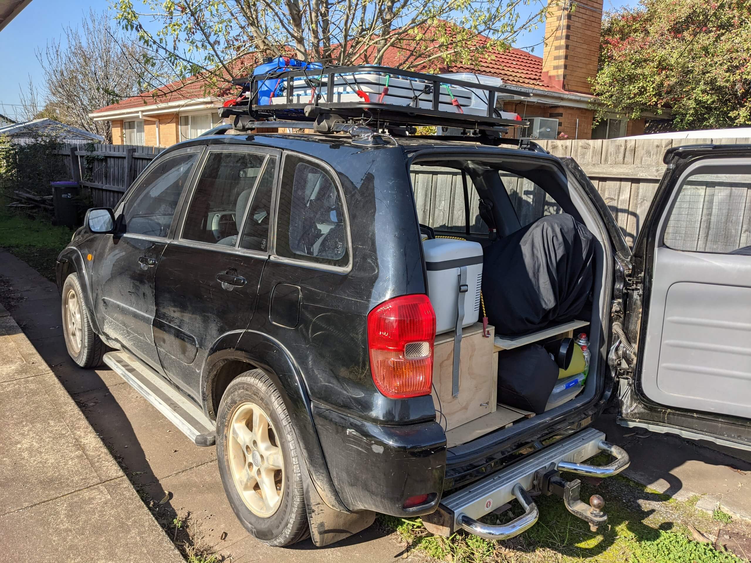 A Toyota RAV4 with the back door open showing it full of camping gear